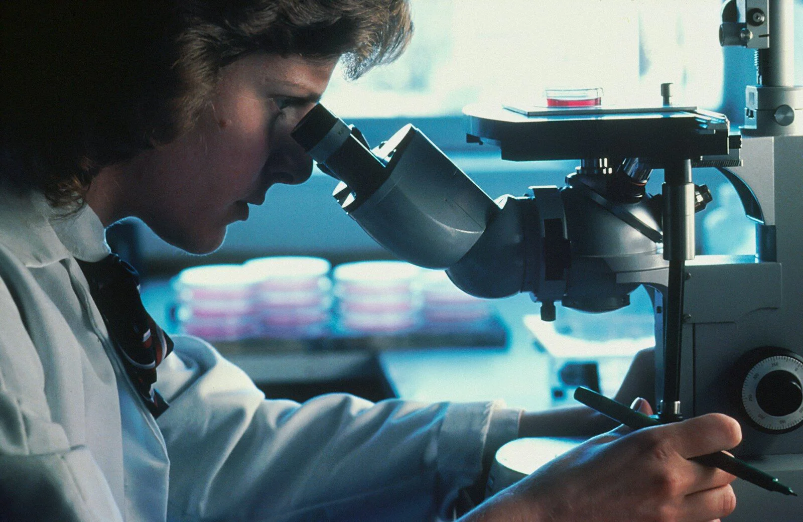 A researcher stares down the viewfinders of a microscope